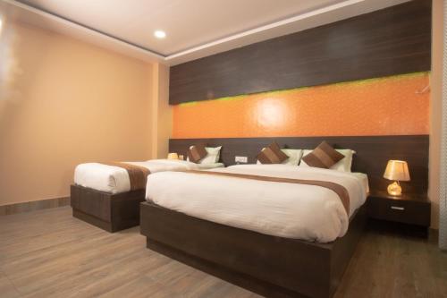 a bedroom with two beds and an orange wall at Annapurna Hotel in Bīrganj