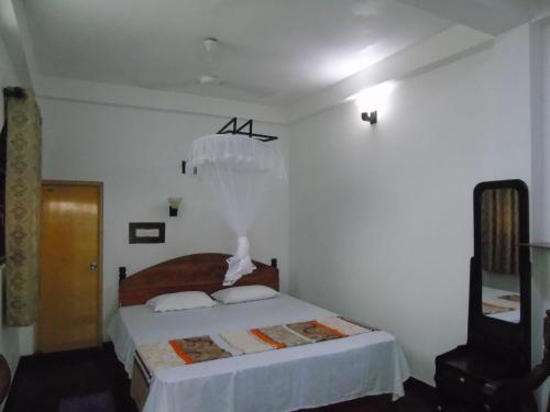 a bedroom with a bed in a white room at Eco Villa - Sinharaja in Deniyaya