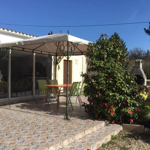 - une table et des chaises sous un parasol sur la terrasse dans l'établissement le gite de la CURE, à Pessac-sur-Dordogne