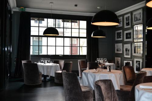 a restaurant with white tables and chairs and windows at Hotel Odette en Ville in Brussels