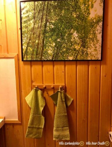 two green towels hanging on a wooden wall at Villa Karhunkehto in Luosto