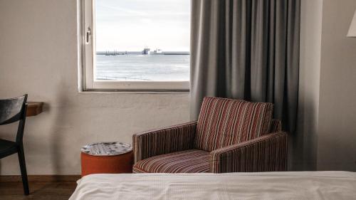 a hotel room with a chair and a window at Home Hotel Magasinet in Trelleborg