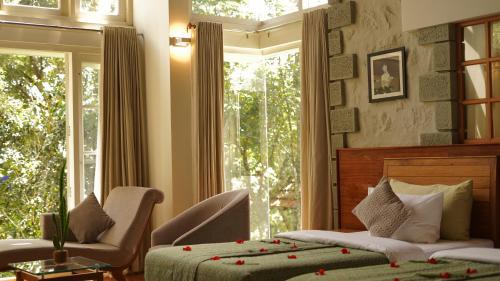 a bedroom with a bed and a chair and a window at SpiceTree Rajakumari in Munnar