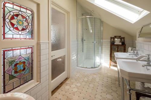 a bathroom with two sinks and a shower and a glass window at Tolcarne Beach Colonial Restaurant and Rooms in Newquay