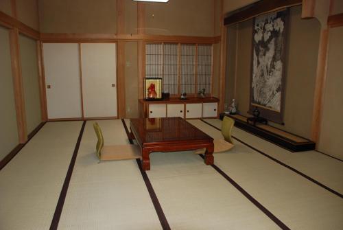 Oshi Ryokan في ناغانو: غرفة معيشة فيها طاولة وكراسي