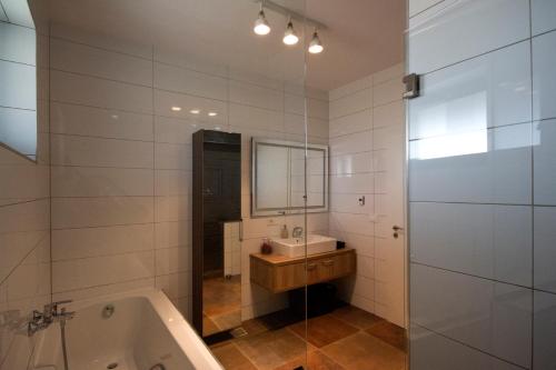 a bathroom with a tub and a sink and a mirror at EdanApartments in Tohanu Nou