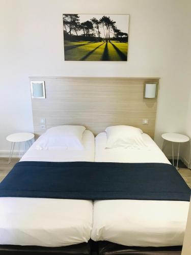 a large bed in a bedroom with two tables at Hippotel in Le Touquet-Paris-Plage
