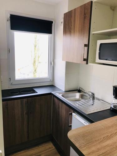 a small kitchen with a sink and a window at Hippotel in Le Touquet-Paris-Plage