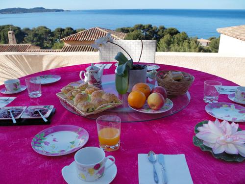 einen Tisch mit einem rosa Tischtuch mit Essen drauf in der Unterkunft Chambres Bellevue in Carqueiranne