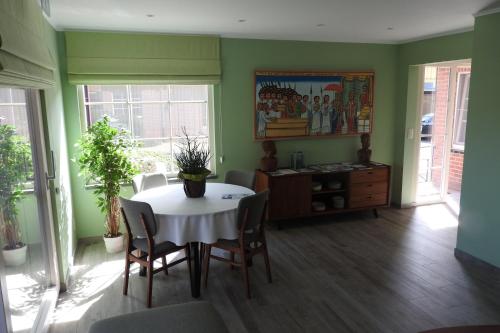una sala da pranzo con tavolo, sedie e pareti verdi di t Sutterhuisje, zalig slapen aan het Donkmeer a Donk