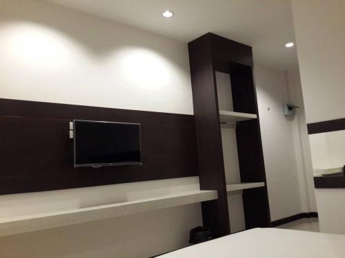 a bedroom with a wall with a tv and shelves at THE ROOM 24 RESORT in Pathum Thani