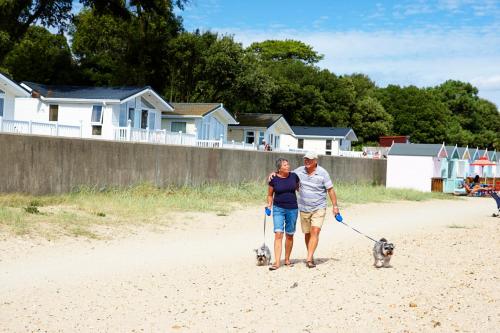 a man and woman walking their dogs on the beach at Sandhills Apartments, Mudeford in Christchurch