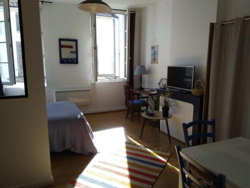 a room with a bed and a desk with a television at Le studio de Line in Rochefort
