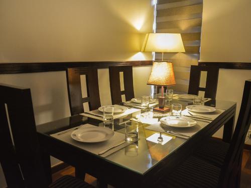 a table with plates and glasses and a lamp on it at Panoramic Holiday Apartment / Seagull Complex | Nuwara Eliya in Nuwara Eliya