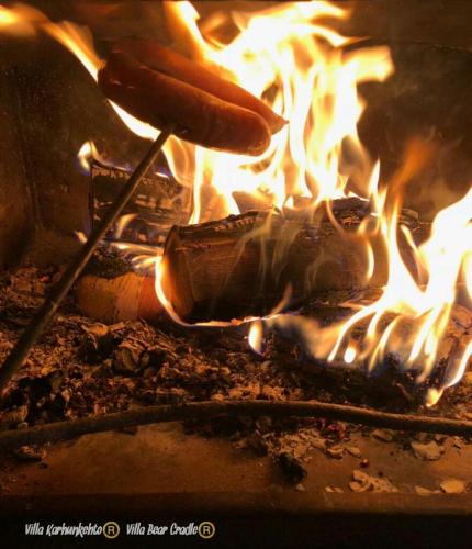 a person cooking a hot dog over a fire at Villa Karhunkehto in Luosto