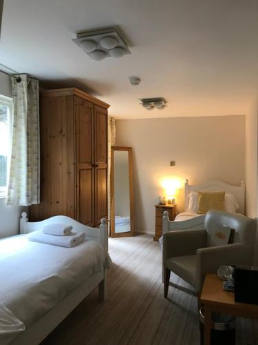 a bedroom with two beds and a chair and a table at The Mariners Hotel in Lyme Regis