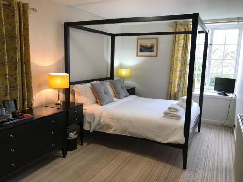 a bedroom with a canopy bed and a television at The Mariners Hotel in Lyme Regis