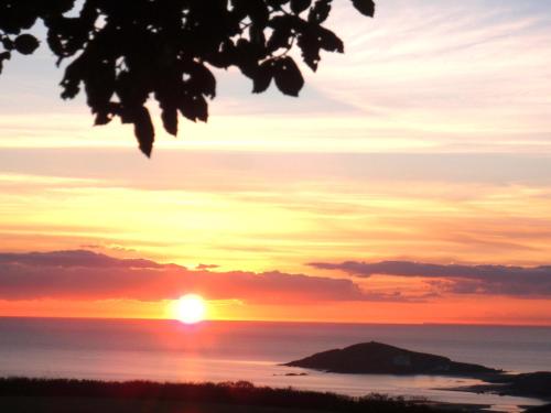a sunset over the ocean with a rock in the foreground at Sunset Lodge in Kingsbridge
