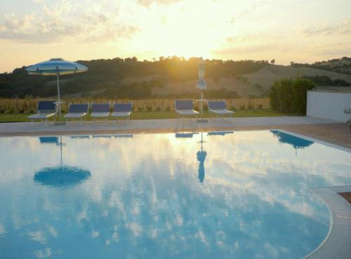 a large swimming pool with chairs and an umbrella at Agriturismo Il Cavallino Saturnia in Semproniano