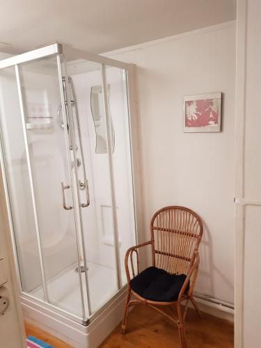 Cette chambre comprend une douche et une chaise en bois. dans l'établissement Quai Peree Apartement, à Saint-Valery-sur-Somme