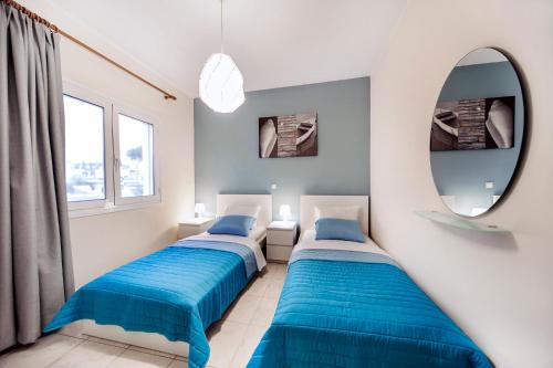 two beds in a room with a mirror at Omega Comfy Apartments in Almyrida