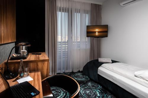a hotel room with a bed and a desk with a laptop at Willa Pieńkowskich in Gdynia