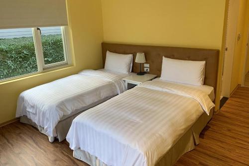 two beds in a hotel room with a window at American Village Resort in Taipei