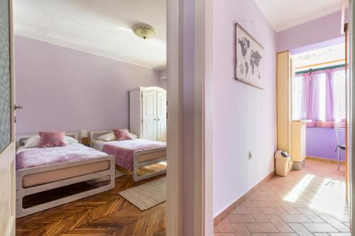 two beds in a room with purple walls and wooden floors at Sunny Apartment Split in Split
