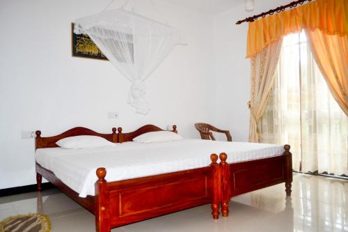 a bedroom with a bed with white sheets and a window at Villa16Hikkaduwa in Hikkaduwa