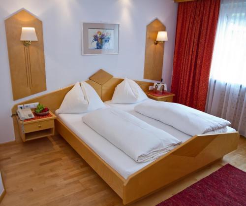 a bedroom with a large bed with white sheets at Pension Clara in Wattens