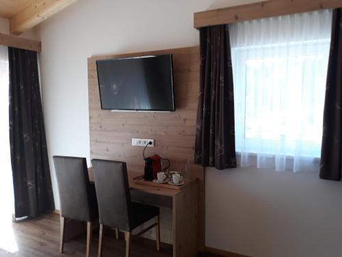 a room with a table and chairs and a television on a wall at Hotel Jagdhof in Kramsach