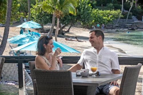 a man and woman sitting at a table at the beach at Secret Harbour Beach Resort in St Thomas