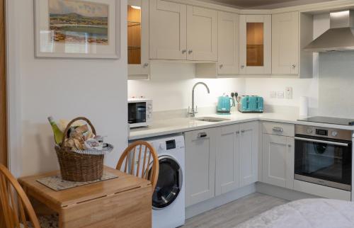 a kitchen with white cabinets and a washing machine at BallyCairn Self Catering Studio in Larne