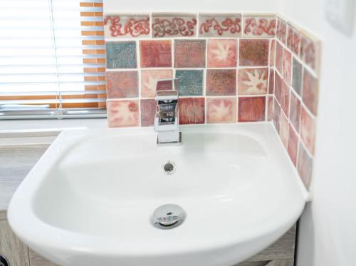 a white sink in a bathroom with a tile wall at BallyCairn Self Catering Studio in Larne
