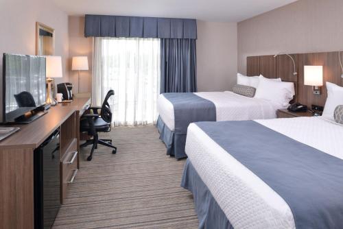 a hotel room with two beds and a desk with a television at Anchored Inn at Hidden Harbor in Deale