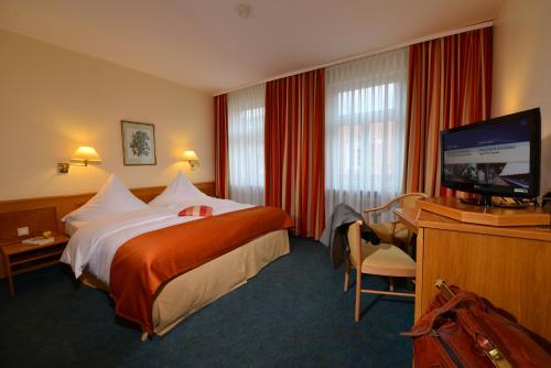 a hotel room with a bed and a flat screen tv at City Partner Hotel Holländer Hof in Heidelberg
