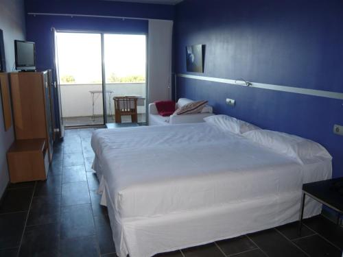 a bedroom with a white bed and a blue wall at Mazagonia in Mazagón