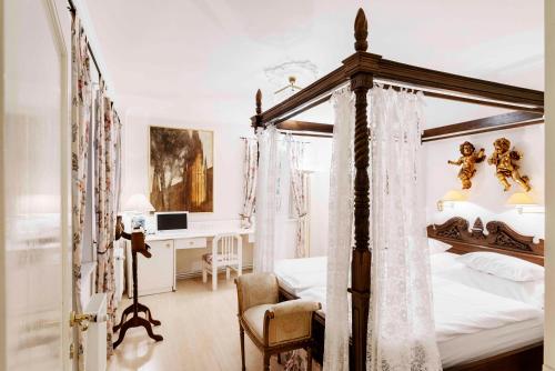 a bedroom with a canopy bed and a desk at Nebozizek Hotel a Restaurant in Prague