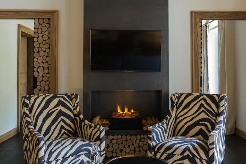 a living room with two chairs and a fire place at House of Hütter - Wachtelhof & SPA in Maria Alm am Steinernen Meer