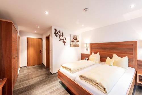 a bedroom with a large bed with a wooden headboard at Hotel Ariadne in Rosenheim