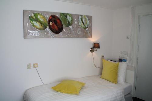 a bed with a yellow pillow and a painting on the wall at De Doelen in Leiden