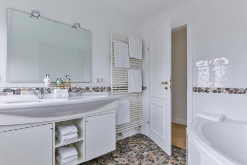 a white bathroom with a sink and a tub at Ferienhaus Lochterbarig in Munkmarsch