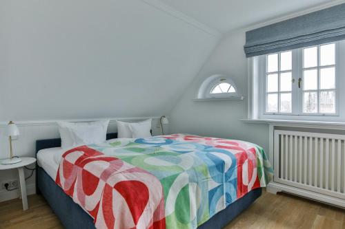 a bedroom with a bed with a colorful blanket at Ferienhaus Lochterbarig in Munkmarsch