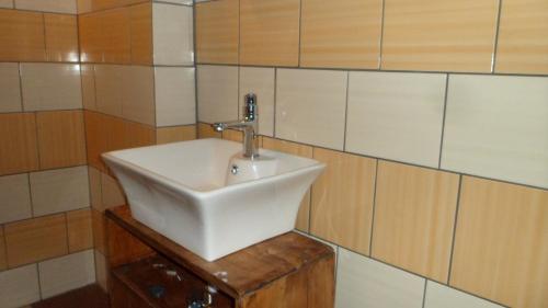 a bathroom with a white sink on a tiled wall at Viruna Farm in Kiraste