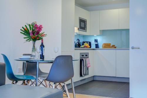 a kitchen with a table and chairs and a vase of flowers at Cleyro Serviced Apartments - Finzels Reach in Bristol