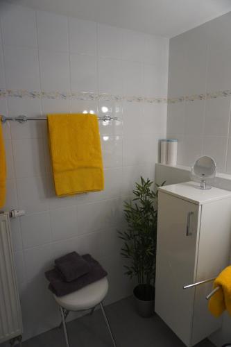 a bathroom with a yellow towel on the wall and a chair at Apartment Regina in Burgberg