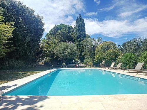 une grande piscine bleue avec des chaises et des arbres dans l'établissement l appentis du chai, à Roujan