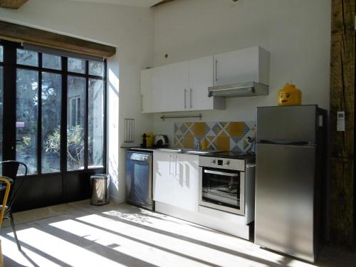a kitchen with white cabinets and a refrigerator at l appentis du chai in Roujan