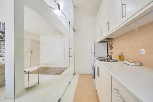 リスボンにあるSalgadeiras Suites - Bairro Altoの白いキャビネットとガラスの壁が備わるキッチン