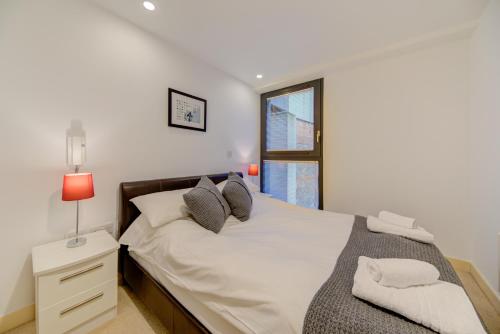 a bedroom with a bed with a lamp and a window at Cleyro Serviced Apartments - Finzels Reach in Bristol